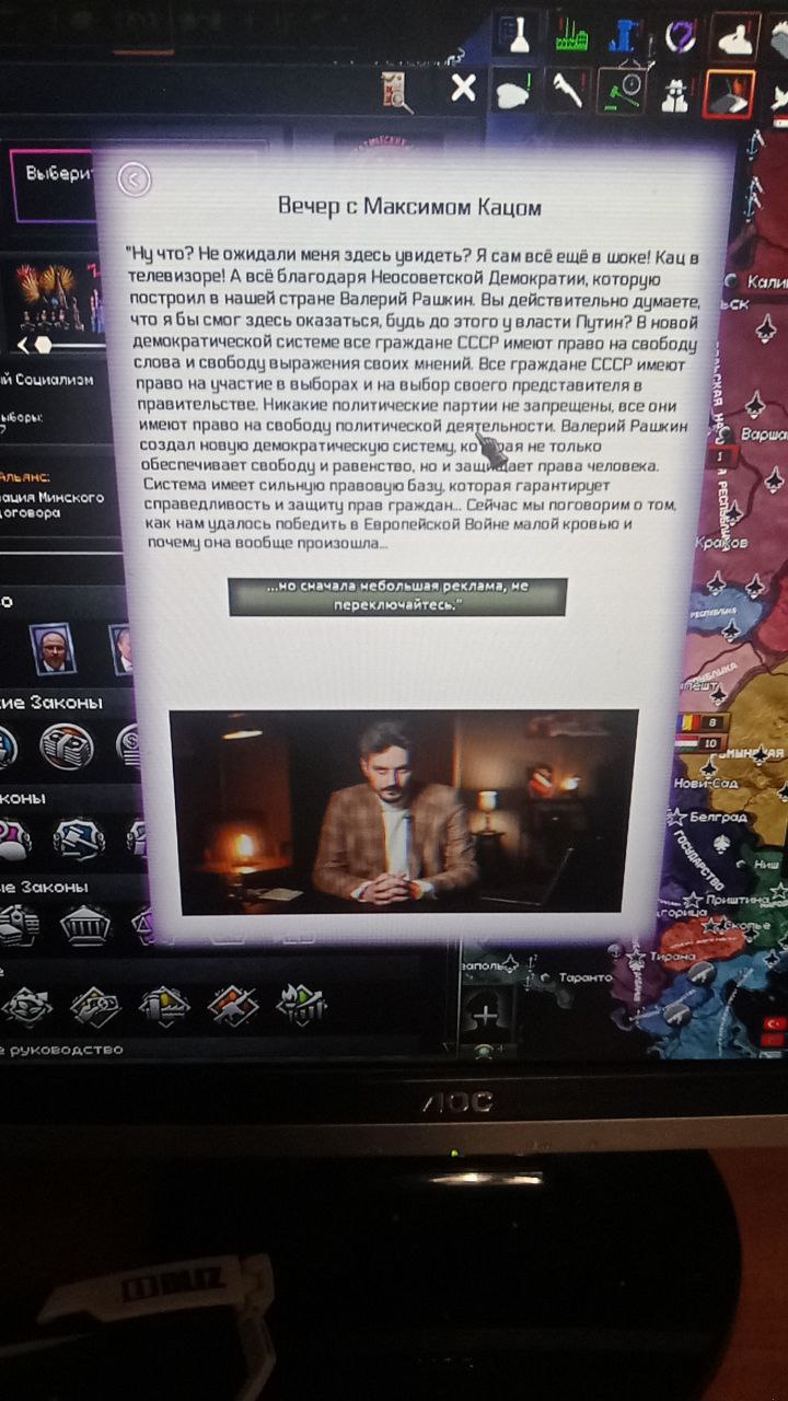 Фото экрана: поверх интерфейса стратегической игры (Crusader Kings или похожей) — наложено окно с текстом «Вечер с Максимом Кацем». Монолог от лица Валерия Рашкина о свободе слова в СССР и демократической системе. Снизу плашка: «но сначала небольшая реклама, не переключайтесь». На фоне — карта Европы с интерфейсом игры.