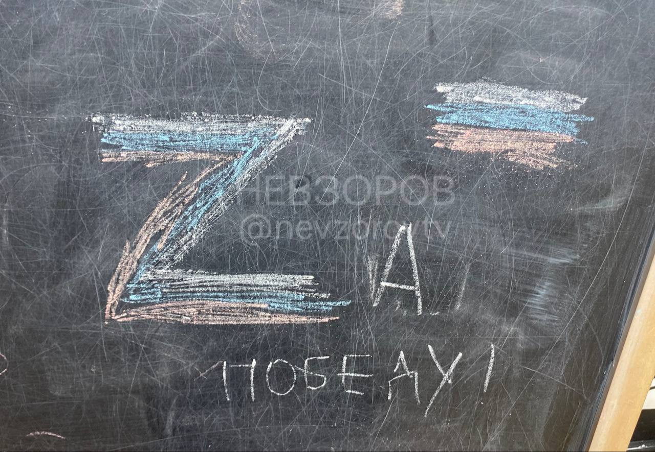Меловая надпись на школьной доске: символ «Z» с нарисованным флагом России и надпись «ЗА ПОБЕДУ!». Водяной знак: nevzborov.ru / @nevzborov_tv.