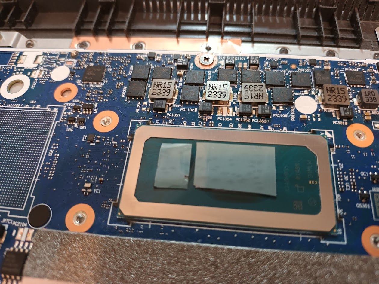 Материнская плата ноутбука крупным планом: синяя PCB, процессор Intel с нанесённым фазовым переходником (серебристая металлическая пластина).