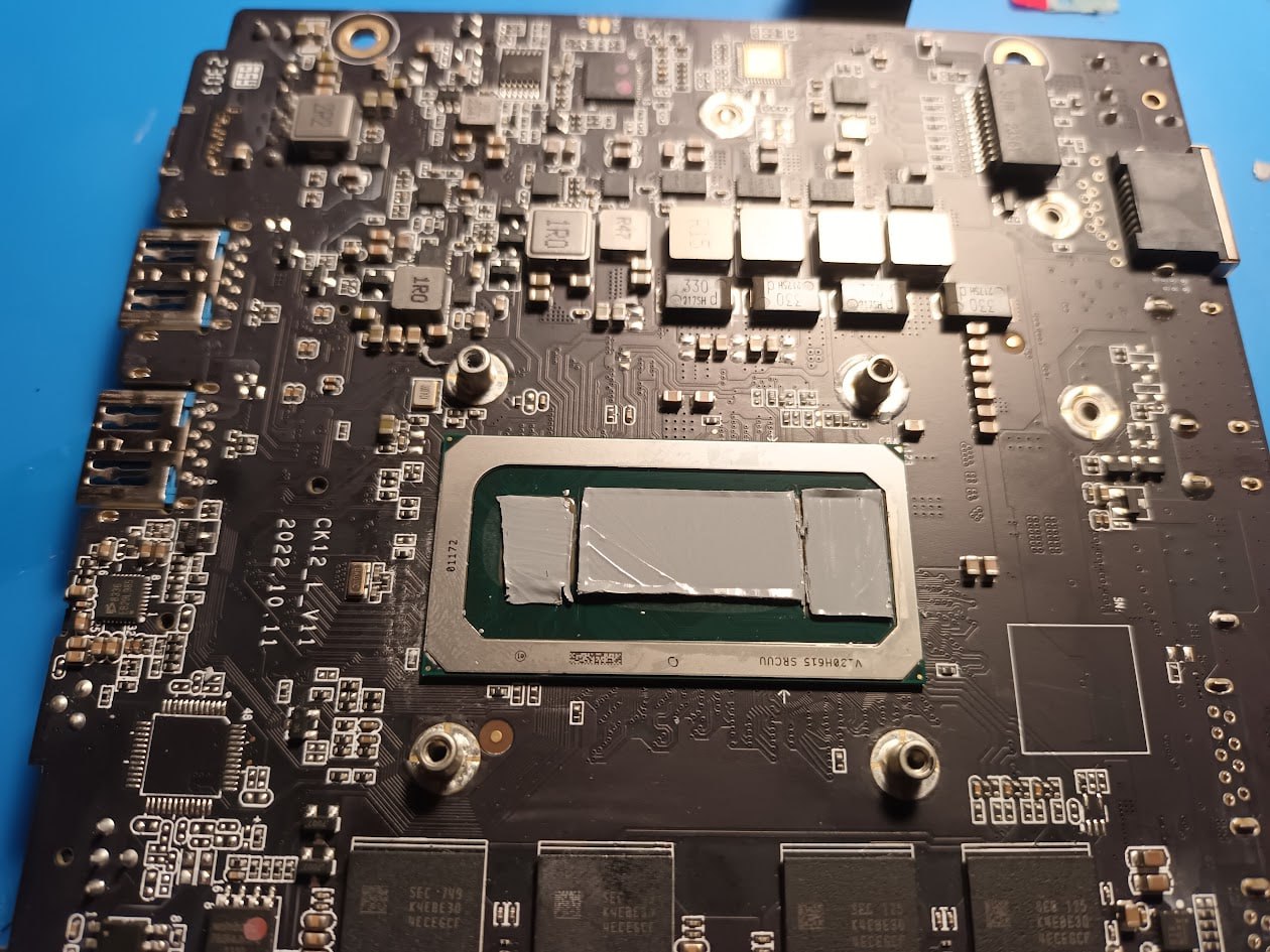 Материнская плата ноутбука: чёрная PCB, процессор с аккуратно наложенным фазовым переходником, вид сверху на рабочей поверхности.