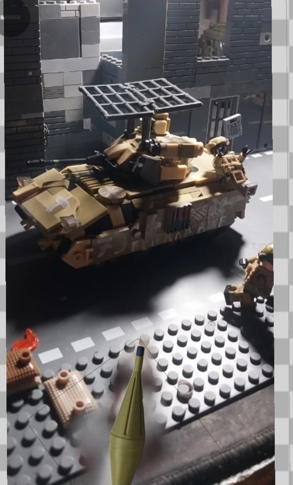 Лего-диорама: танк Abrams с решётчатой защитой, фигурки солдат и снаряд.