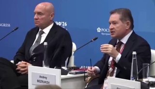 Стоп-кадр: конференция, двое мужчин за столом на фоне баннера ПМЭФ. Табличка «Andrey BEZRUKOV» — Андрей Безруков, профессор МГИМО и полковник СВР.