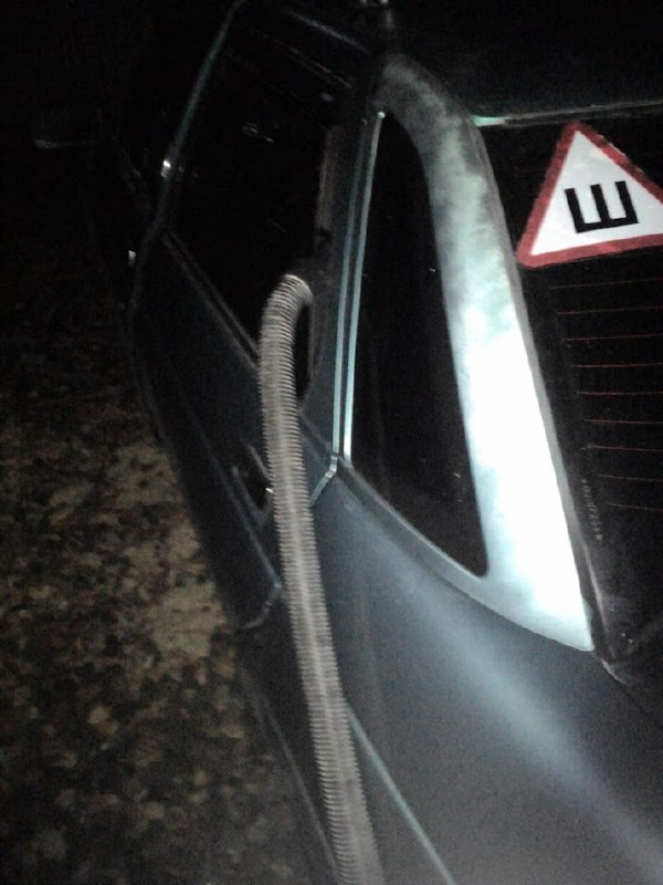 Фото снаружи автомобиля: шланг пропущен через окно, на заднем стекле наклейка «Ш» (начинающий водитель).