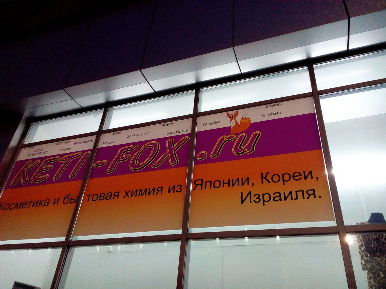 Ночная витрина магазина KETI-FOX.ru: бело-оранжево-фиолетовая вывеска с лисой, надпись «Косметика и бытовая химия из Японии, Кореи, Израиля», перечислены бренды Kose, SOFTYMO, Rosette, Privia, Laura Rosse и др.