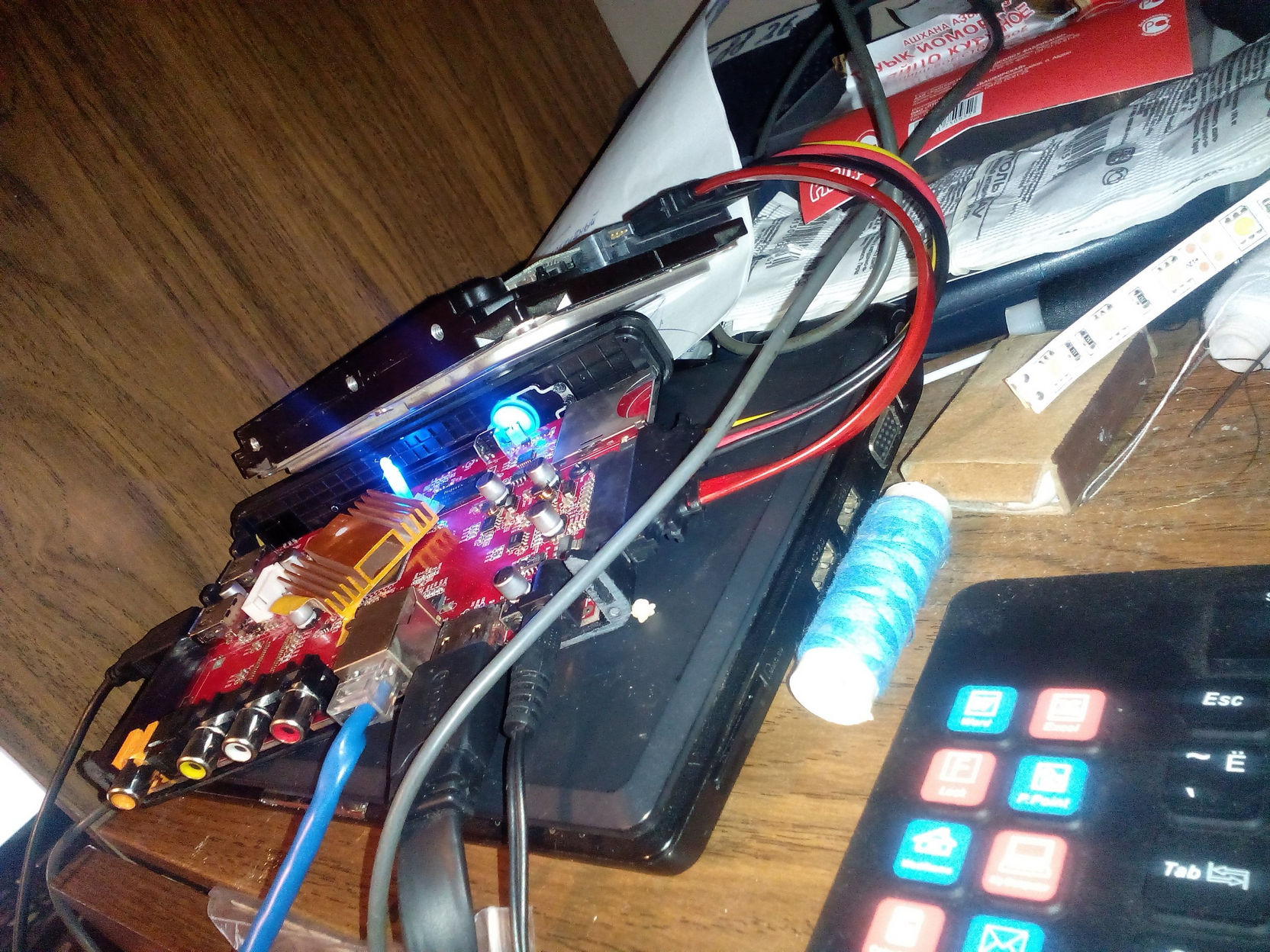 Готовая DLNA-приставка на рабочем столе: плата HD600A с синей подсветкой, подключены провода питания, HDMI, жёсткий диск; рядом мини-клавиатура
