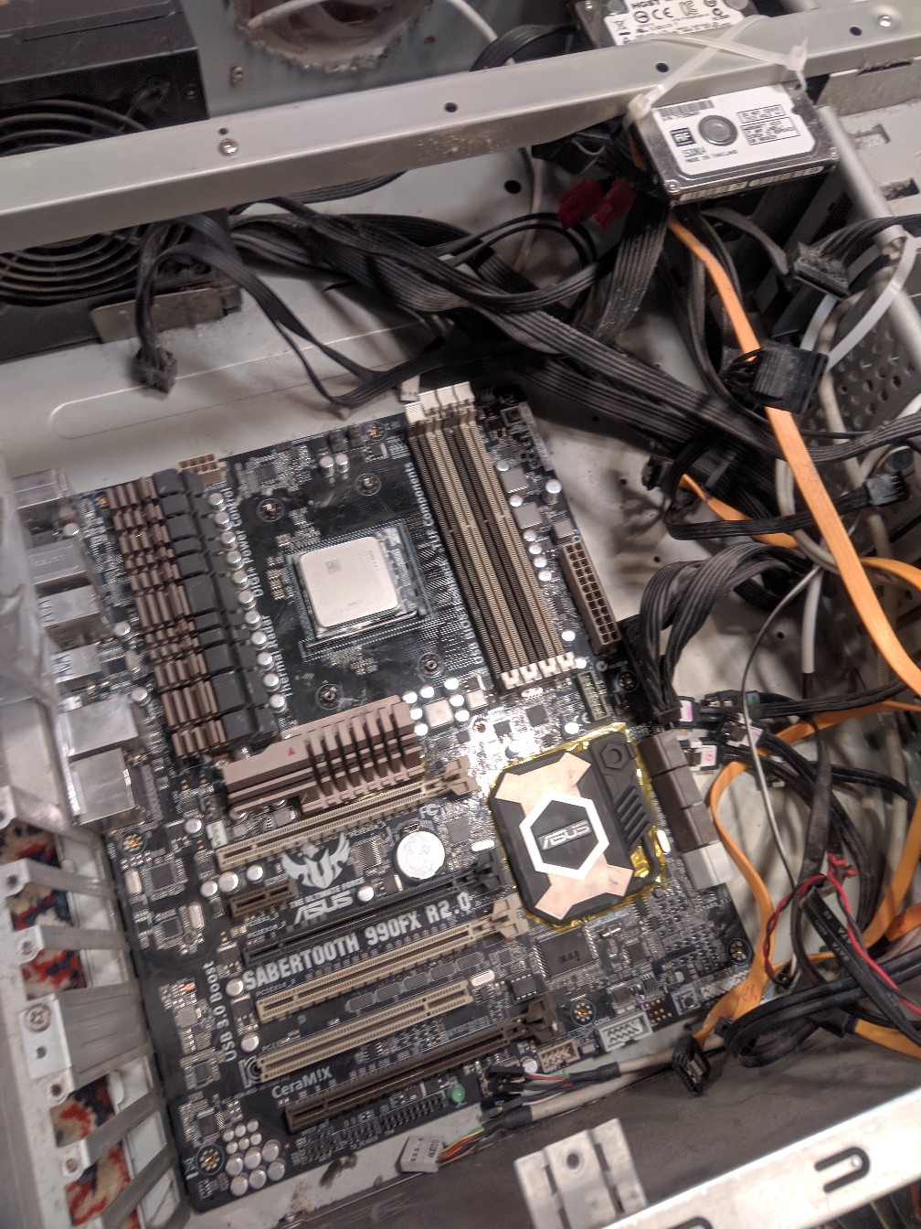 Открытый корпус системного блока: материнская плата ASUS Sabertooth 990FX R2.0 с процессором AMD и кулером, провода SATA, HDD, блок питания