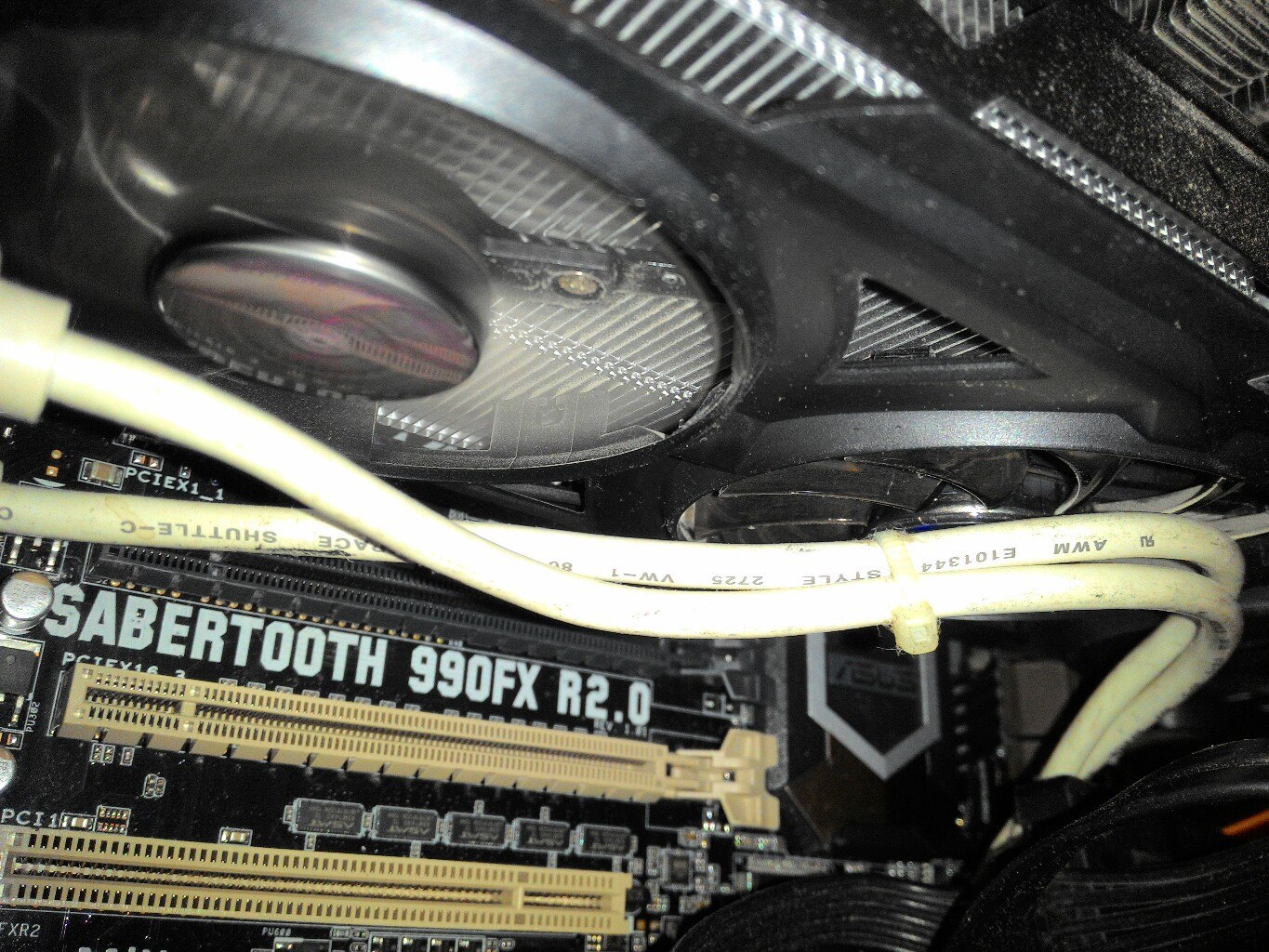 Внутренности корпуса ПК: материнская плата ASUS SABERTOOTH 990FX R2.0 с видимыми слотами PCI-E; сверху — массивный кулер с двумя вентиляторами; белый кабель (питание) проложен прямо поверх платы и вентиляторов кулера — наглядный пример «как не надо укладывать кабели»