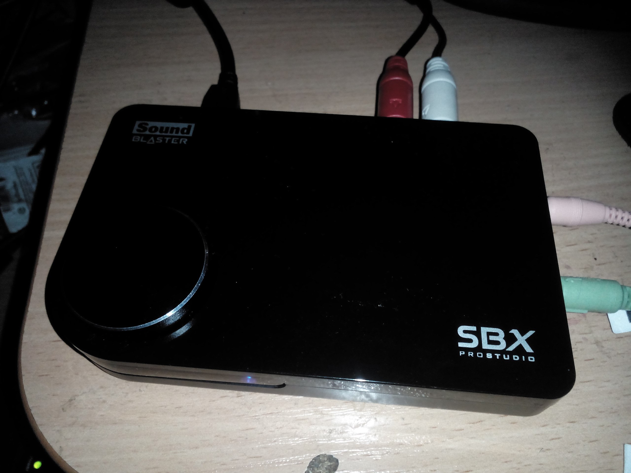 Внешняя звуковая карта Creative Sound Blaster SBX Pro Studio: чёрный прямоугольный корпус с регулятором громкости, красный и белый аудиоразъёмы, USB-кабель