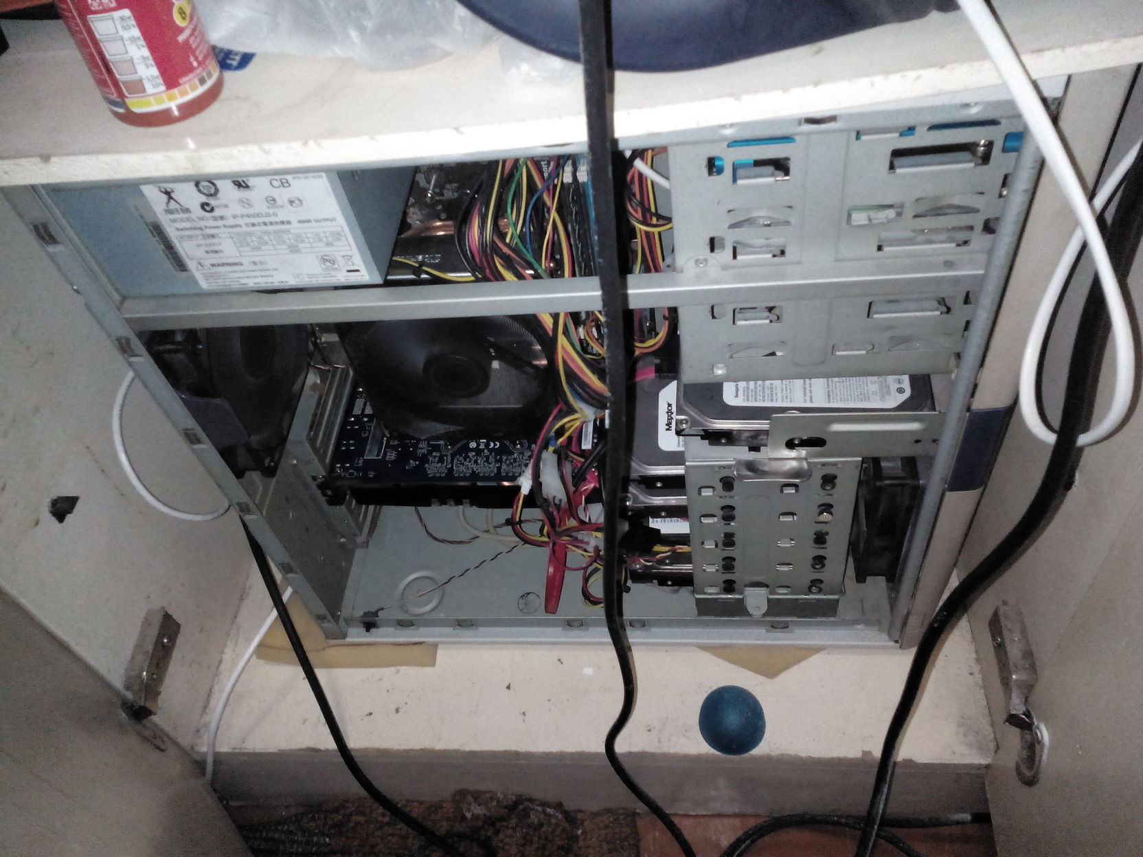 Открытый системный блок, вид снизу ниши: HDD Maxtor, разноцветные провода, DVD-привод; огнетушитель на полке сверху