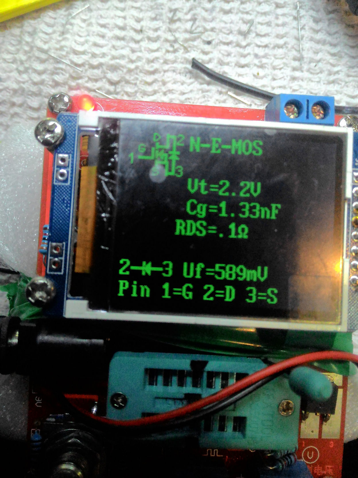 Скриншот экрана тестера компонентов (зелёный текст на чёрном): «N-E-MOS / Vt=2.2V / Cg=1.33nF / RDS=.1Ω / 2-M-3 Uf=589mV / Pin 1=G 2=D 3=S»