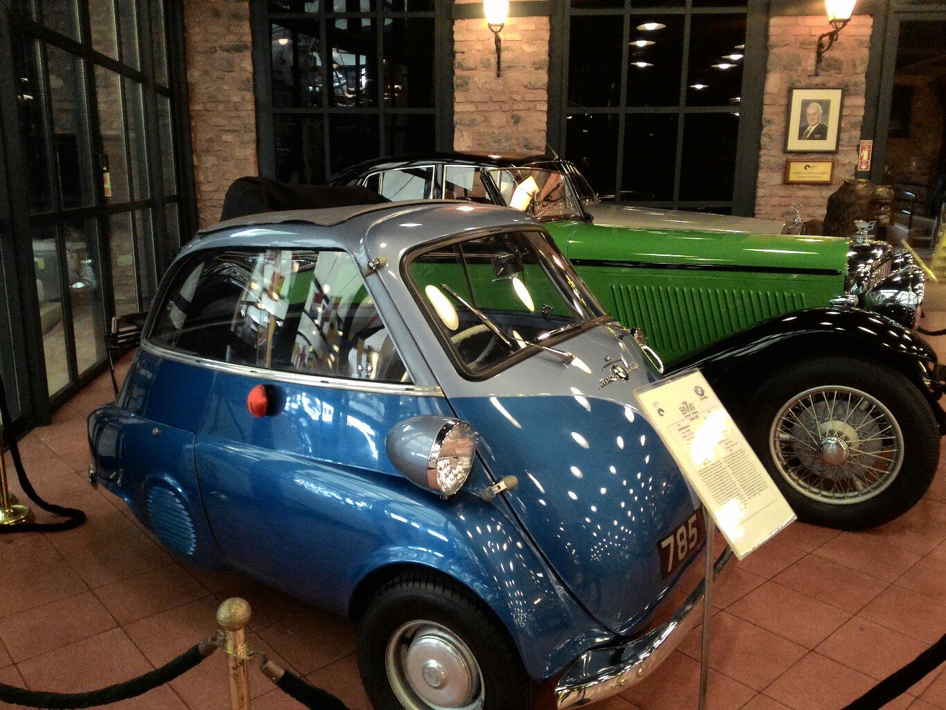 Зал музея Рахми Коча в Стамбуле: на переднем плане — голубая BMW Isetta (микроавтомобиль, табличка с номером 785); сзади — большой зелёный ретро-автомобиль 1930-х годов; кирпичные стены, тёплое музейное освещение