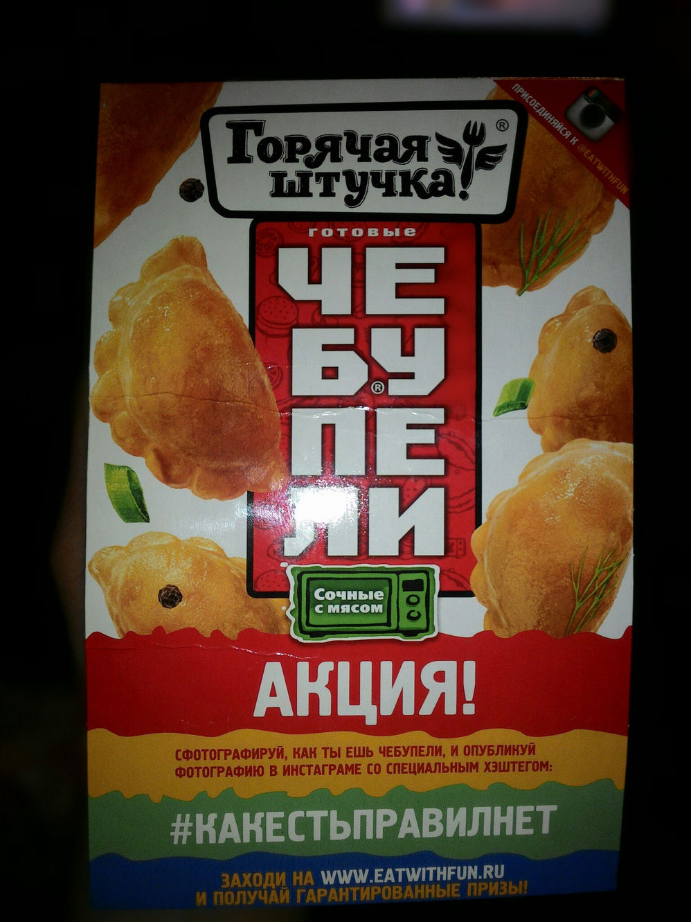 Коробка замороженных чебупелей «Горячая штучка!» (готовые ЧЕБУПЕЛИ, сочные с мясом, для микроволновки); снизу — красная надпись «АКЦИЯ!»: «Сфотографируй, как ты ешь чебупели, и опубликуй фотографию в инстаграме со специальным хэштегом: #КАКЕСТЬПРАВИЛНЕТ. Заходи на www.eatwithfun.ru и получай гарантированные призы!»