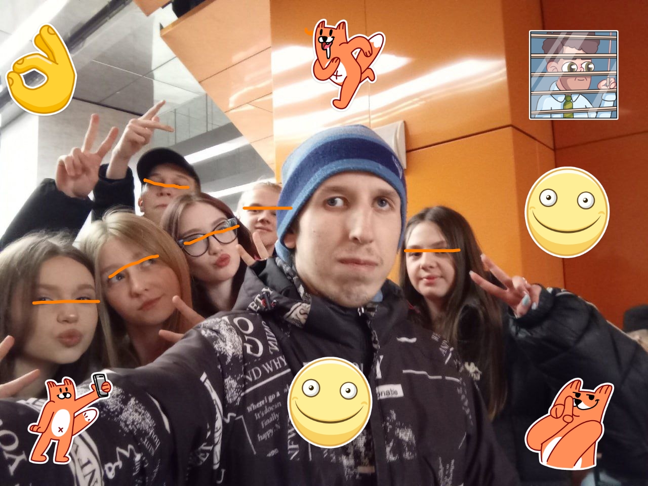 📷 Selfie «Артем Лаптев» в помещении с группой ~6 молодых людей (в основном девочки/девушки); лица закрыты оранжевыми геометрическими фигурами; поверх — фурри-стикеры и смайлики.
