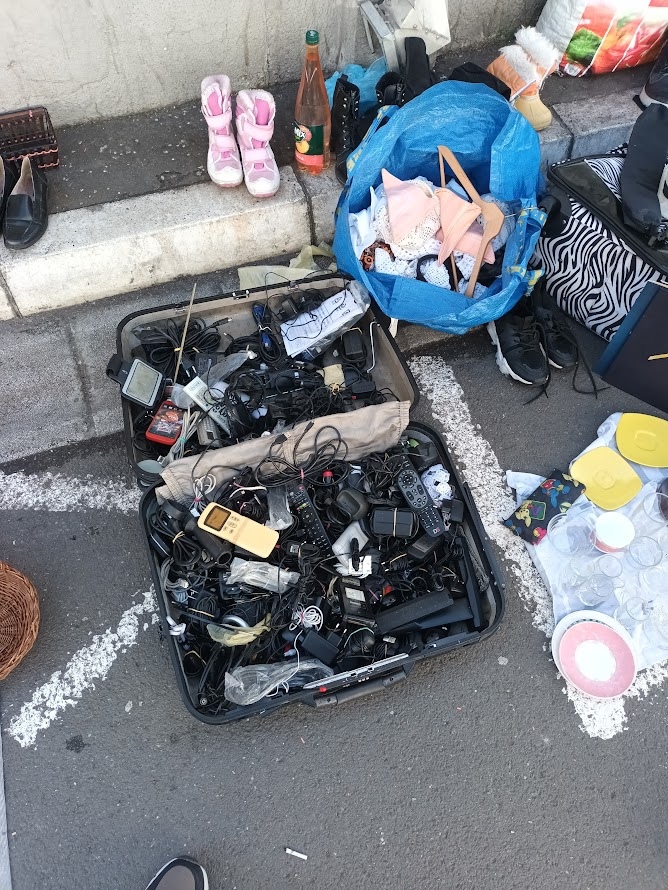 📷 Раскрытый пластиковый чемодан со старыми зарядными устройствами, телефонами Motorola, кабелями и прочей электроникой.