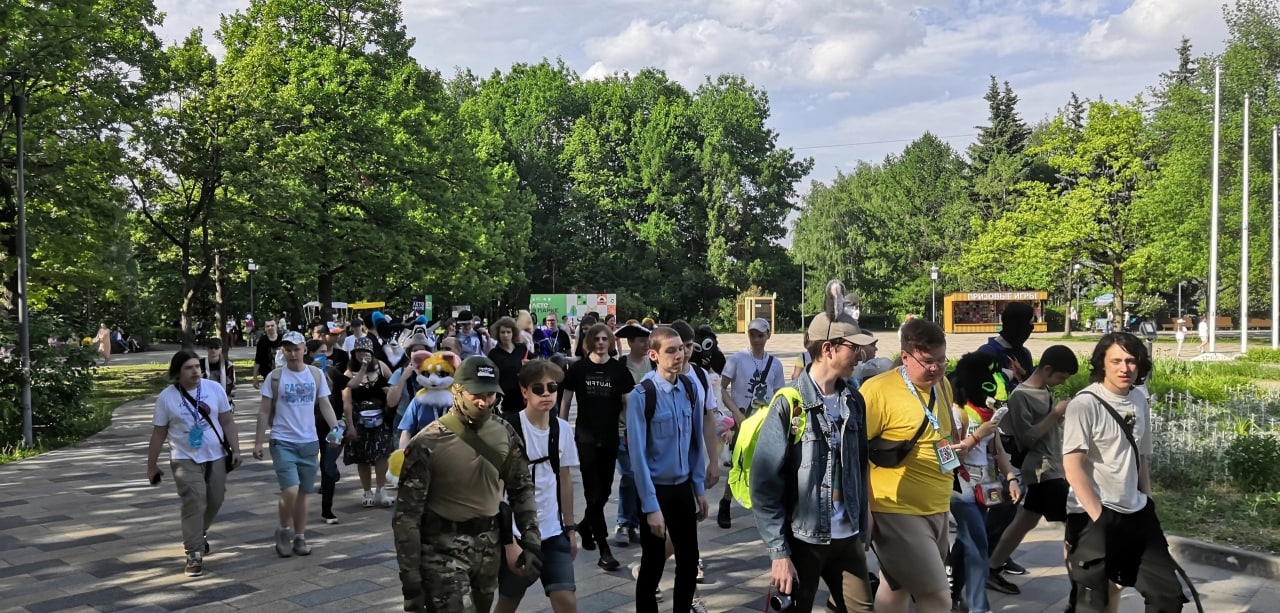 📷 Группа людей идёт по бульвару в парке; у некоторых жёлтые куртки.