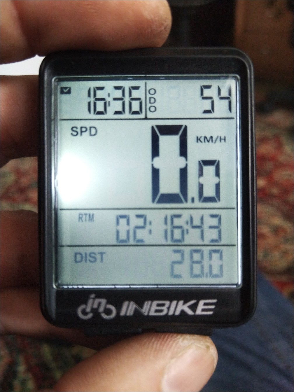 Велокомпьютер INBIKE в руке: время 16:36, ODO 54, SPD 0.0 KM/H, RTM 02:16:43, DIST 28.0 — итог поездки на самокате 28 км