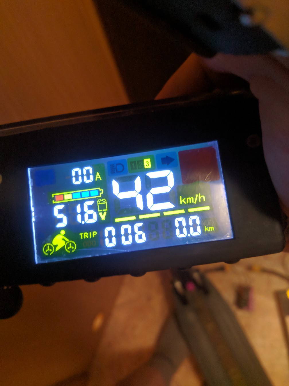 Цветной LCD-дисплей электросамоката крупным планом: 0.0A, 51.6V, большие жёлтые цифры 42 km/h по центру, TRIP 0.06, индикатор заряда батареи