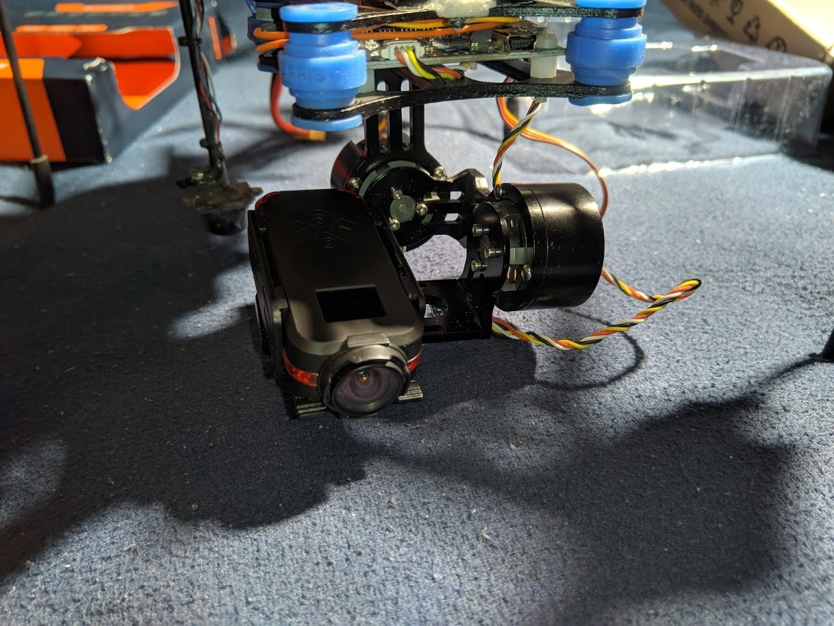 📷 Трёхосевой подвес (gimbal) с FPV-камерой крупным планом: синие и оранжевые моторы подвеса, чёрный корпус камеры