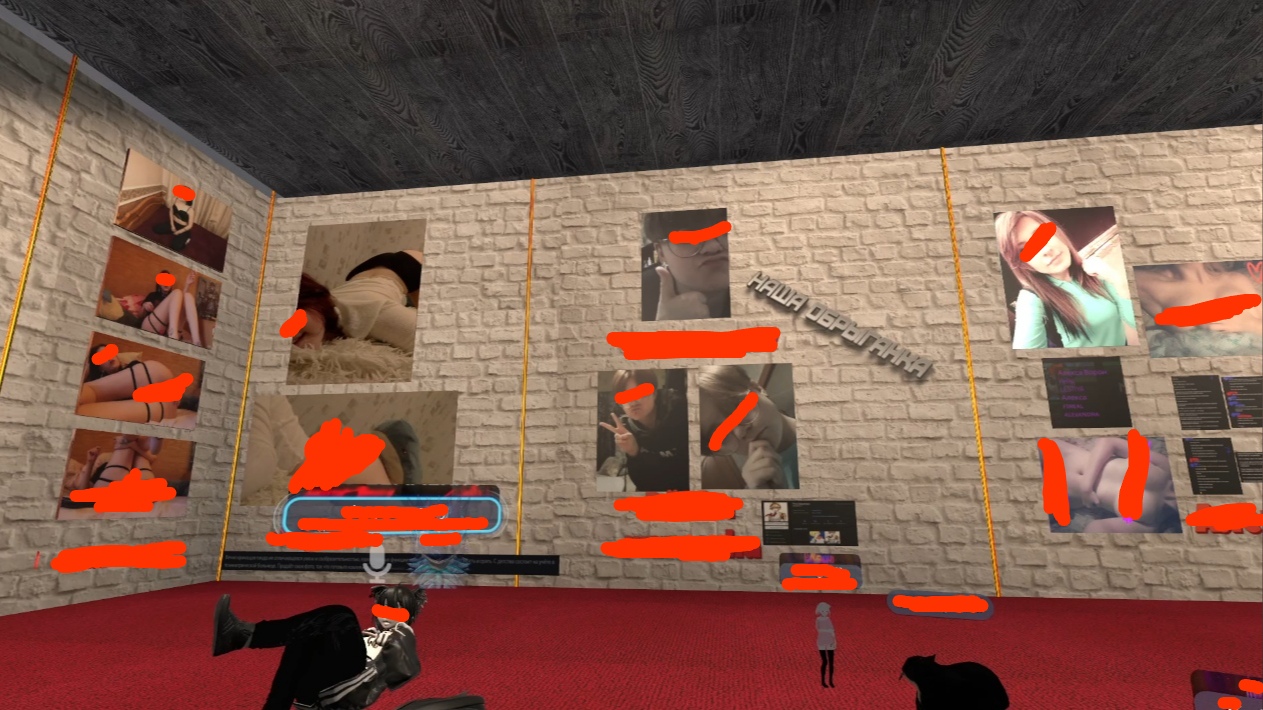 📋 VRChat: галерея интерьер — стена с несколькими фотографиями (лица закрашены красным), надпись «НАША СЕРАЯ КАКА»; на красном ковре лежит аватар-персонаж, два игрока стоят.