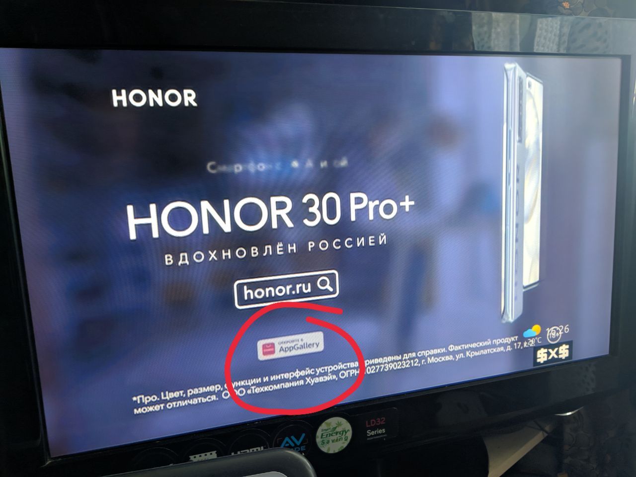 Фото телевизора с рекламой: «HONOR / HONOR 30 Pro+ / ВДОХНОВЛЁН РОССИЕЙ / honor.ru / AppGallery [обведён красным кружком] / *Про. Цвет, размер, функции и интерфейс устройства могут отличаться. ООО «Техкомпания Хуавэй», ОГРН: 027739023212, Москва, ул. Крылатская, д. 17»