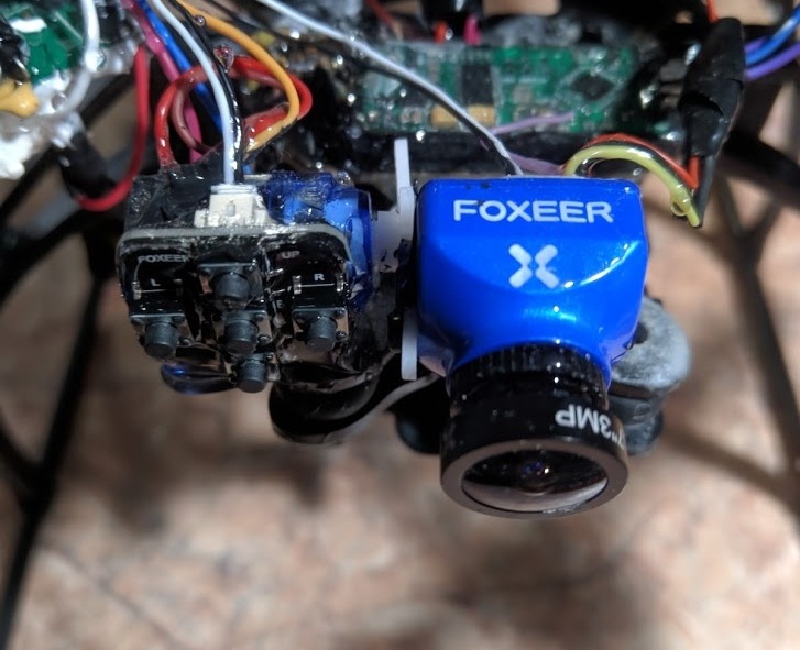 Крупный план передней части FPV-квадрокоптера: синяя камера FOXEER 3MP на стойке и блок двух FPV-камер (с надписями L/R), провода, электронные платы