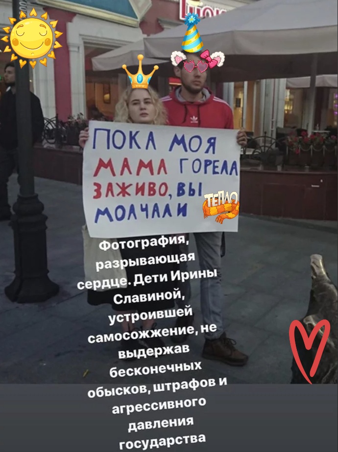 📋 Скриншот Instagram-истории: молодой человек держит плакат «ПОКА МОЯ МАМА ГОРЕЛА ЗАЖИВО, ВЫ МОЛЧАЛИ» (наклейки «солнышко», «корона», «ТЕПЛО»); подпись: «Фотография, разрывающая сердце. Дети Ирины Славиной, устроившей самосожжение, не выдержав бесконечных обысков, штрафов и агрессивного давления государства»