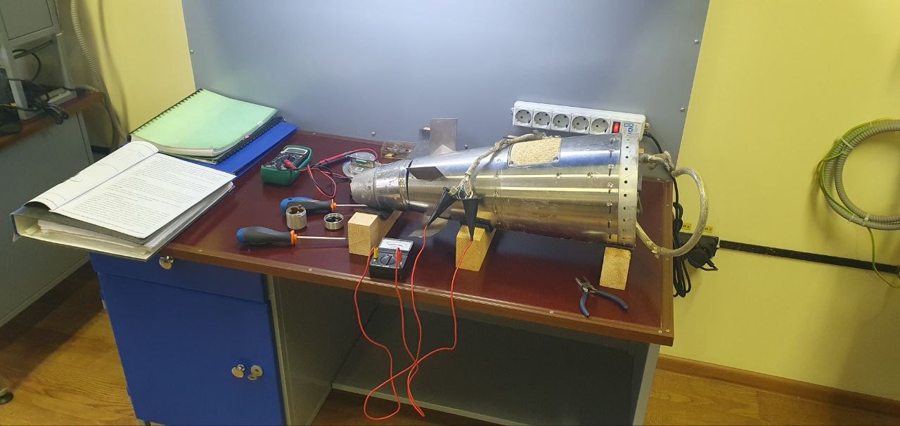 📷 Детальный снимок металлического цилиндра (предполагаемая ракета РСЗО HIMARS) на рабочем столе с инструментами, приборами, документами и папками.