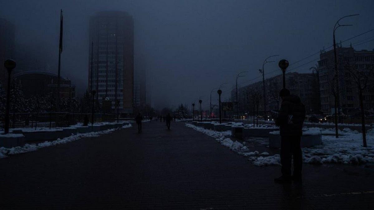 📷 Тёмная зимняя ночь: широкий бульвар в густом тумане, снег на земле, силуэты прохожих, фонарные столбы, высотное здание на заднем плане — город полностью обесточен.