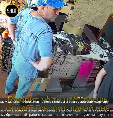 📷 Кадр SHOT: мужчина в синей футболке и кепке работает с компьютерными комплектующими; субтитры: «Говорит: чё ты наё**ваешь людей?... бракованный графический адаптер».