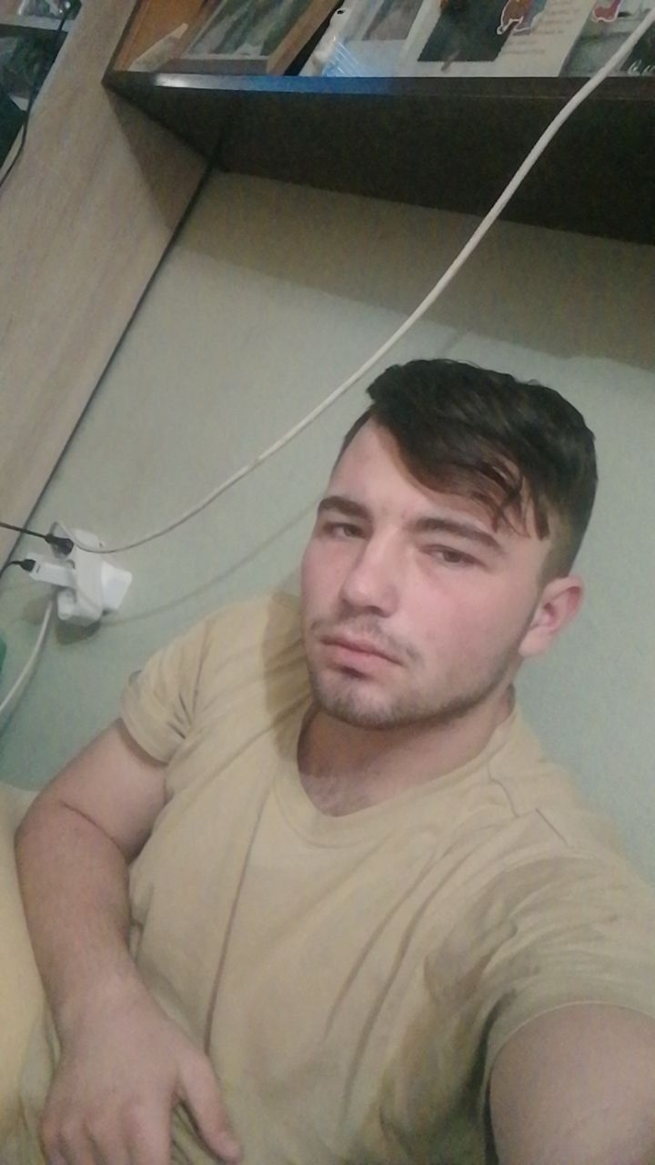 📷 Молодой мужчина в бежевой футболке, отдыхает на кресле под виноградными листьями.