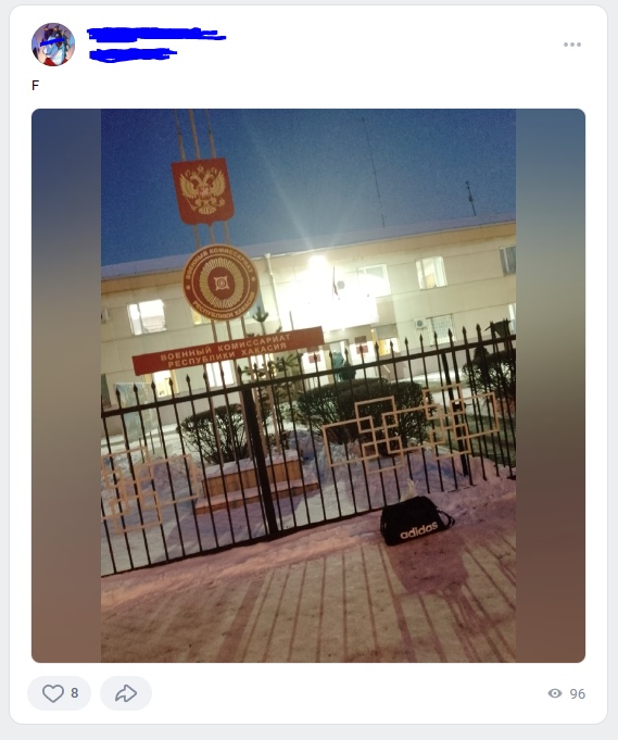 📋 ВКонтакте, пост с размытыми аватаром и именем; текст «F»; фото: здание военного комиссариата зимним вечером — металлический забор, вывеска «ВОЕННЫЙ КОМИССАРИАТ», подсветка, сугробы; перед воротами на снегу лежит сумка Adidas; 8 лайков, 96 просмотров.