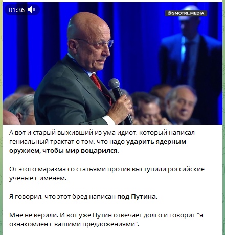 📋 Скриншот видео (01:36) из @smotri_media — пожилой мужчина в зелёном пиджаке и галстуке выступает в зале; подпись: «А вот и старый выживший из ума идиот, который написал гениальный трактат о том, что надо ударить ядерным оружием, чтобы мир воцарился. От этого маразма со статьями против выступили российские учёные с именем. Я говорил, что этот бред написан под Путина. Мне не верили. И вот уже Путин отвечает долго и говорит «я ознакомлен с вашими предложениями».»